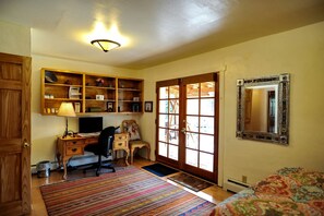 A room with a desk, computer, chair, and a large mirror.