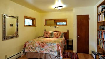Un dormitorio con cama, estantería, puerta, espejo y ventana.
