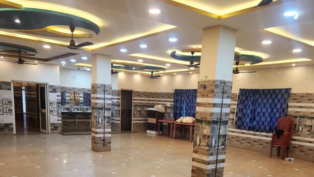 A spacious lobby with a polished marble floor, ceiling fans, recessed lighting, and a seating area with a table and chairs. - Swayamsiddha Continental (Kendrapara)
