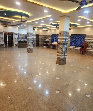 A spacious lobby with a polished marble floor, ceiling fans, recessed lighting, and a seating area with a table and chairs. - Swayamsiddha Continental (Kendrapara)