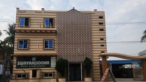 A hotel with a patterned facade, a sign for 'Swayamsiddha Hotel & Restaurant,' and a gated entrance. - Swayamsiddha Continental (Kendrapara)