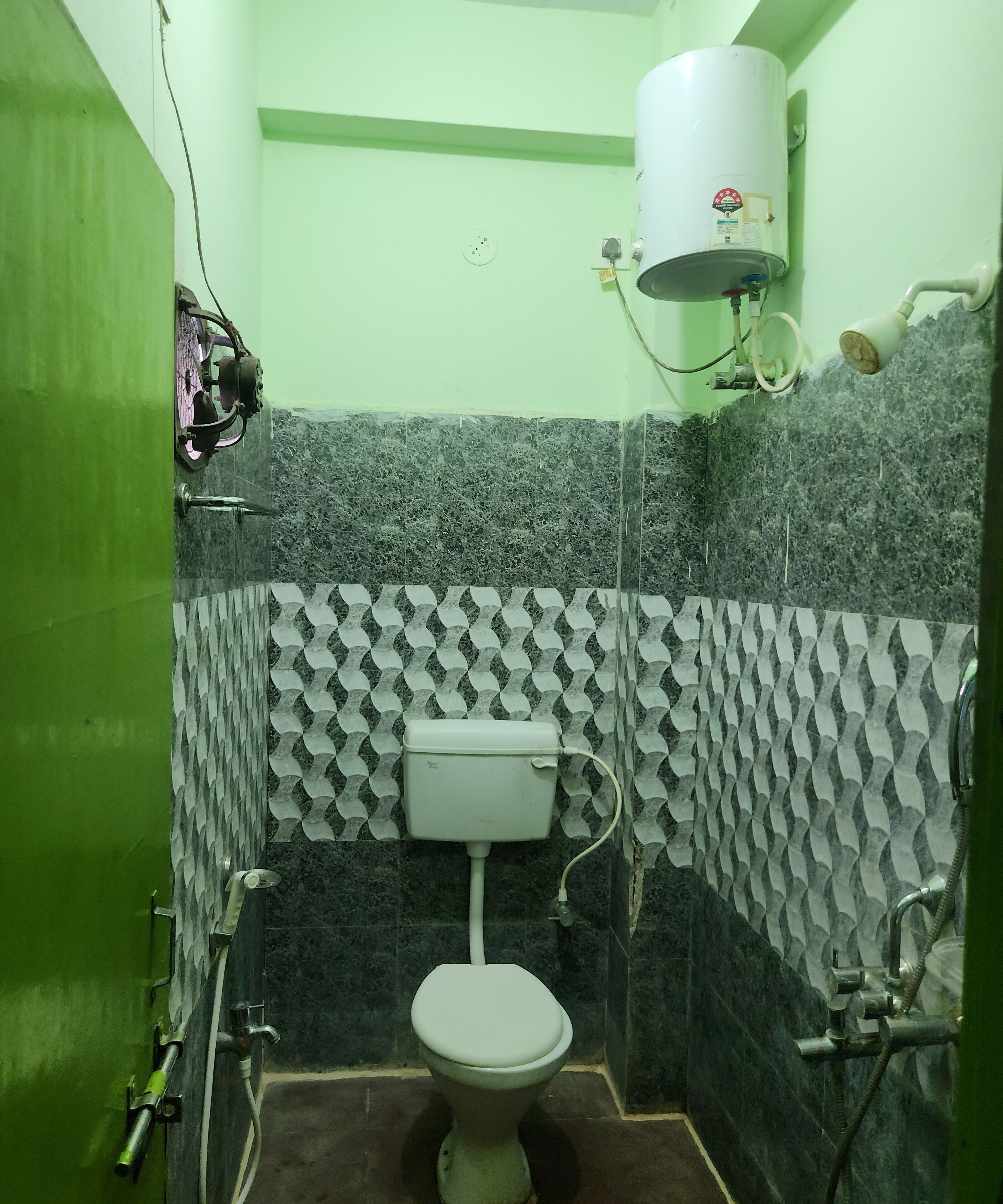 Ein Badezimmer mit Toilette, Warmwasserbereiter und Dusche.