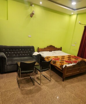 A room with a bed, a sofa, and two chairs.