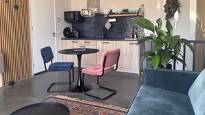 Ett modernt kök med en svart bänkskiva, en mikrovågsugn och en kaffemaskin. Det finns en matplats med ett runt bord och två stolar.