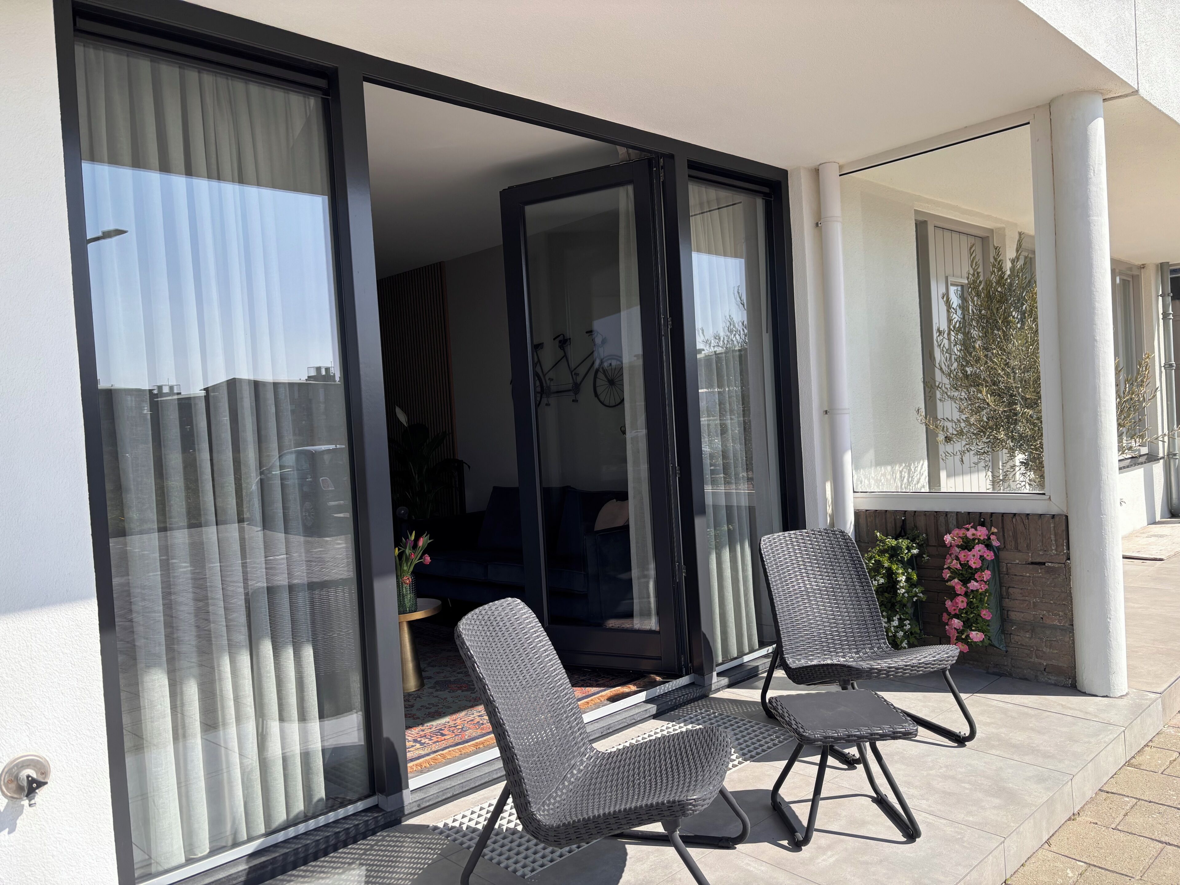 Un balcon avec deux chaises, une porte-fenêtre coulissante et une vue sur l’intérieur.