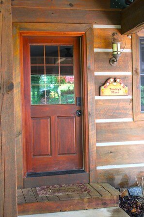 A wooden door with a glass panel, a small shelf with a sign, and a welcome mat. - Tracey's Gem Cabin Franklin, NC (Franklin)