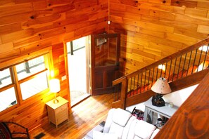 A wooden cabin interior with a staircase, a small table with a lamp, and a chair. - Tracey's Gem Cabin Franklin, NC (Franklin)