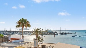 A marina with boats, a palm tree, and a clear sky. - B-rent Bluemarlin Boutique Sea View – Central Apartment with Stunning Ocean Views (Corralejo)