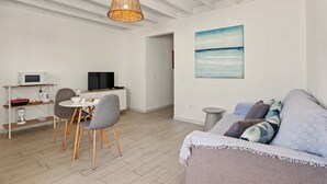 A modern living room with a dining area, a television, and a painting on the wall. - B-rent Bluemarlin Boutique Sea View – Central Apartment with Stunning Ocean Views (Corralejo)