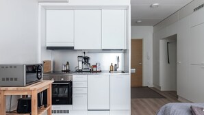 A modern kitchen with white cabinets, a built-in oven, a coffee maker, and a microwave.