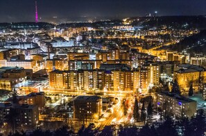 Yökuva kaupunkimaisemasta, jossa on valaistuja rakennuksia, huomiota herättävä torni ja lumipeitteinen alue.