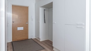 A hallway with a wooden door, a white wardrobe, a coat rack, and a patterned mat.