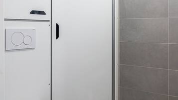 A modern bathroom with a toilet, a white cabinet, and a shower area.