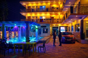 A hotel with a pool area, outdoor seating, and a car parked in front. - DREAM BASANTI (Mandarmani)