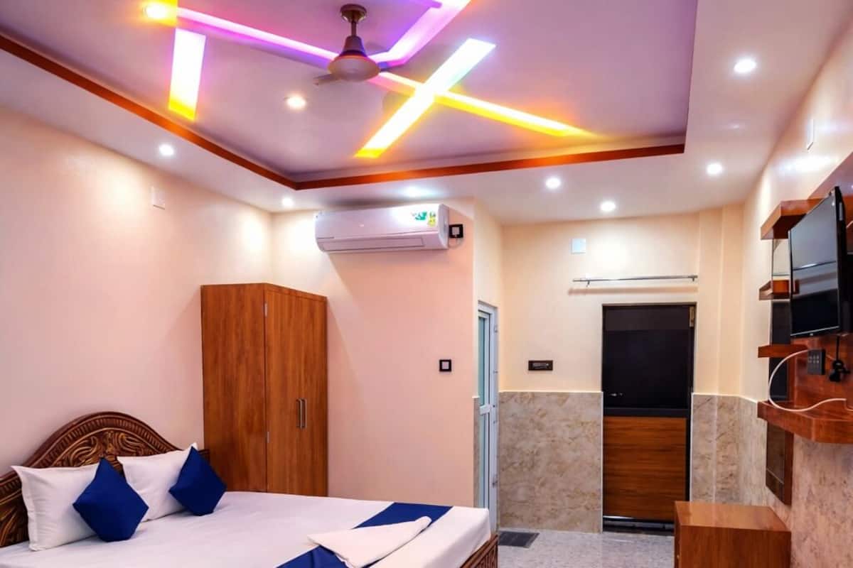 A hotel room with a bed, wardrobe, vanity, and a television.