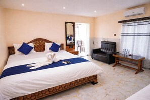 A hotel room with a bed, a TV, a desk, and an air conditioning unit. - DREAM BASANTI (Mandarmani)