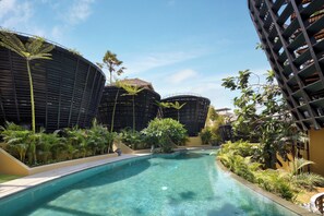 Una piscina envoltada de vegetació abundant i arquitectura moderna.