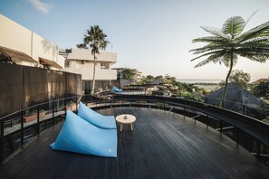 Una terrassa a la teulada amb un seient de trama blau, una taula rodona petita i una palmera.