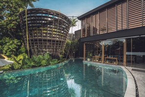 Edifici modern amb piscina, envoltat de vegetació exuberanta.