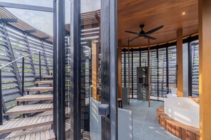 A modern interior with a wooden staircase, a ceiling fan, and a circular seating area. - Romantic 1BR Villa with Rooftop Sea Views (Canggu)