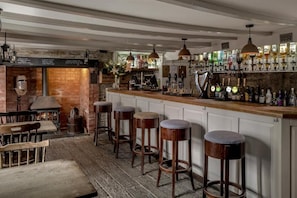 A bar area with stools, a brick wall, and a wooden counter.
