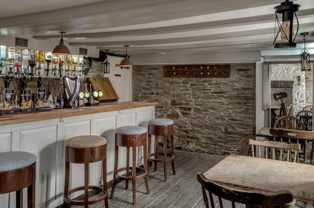 Eine Bar mit Hockstühlen, einer Holztresen und einer Steinwand.
