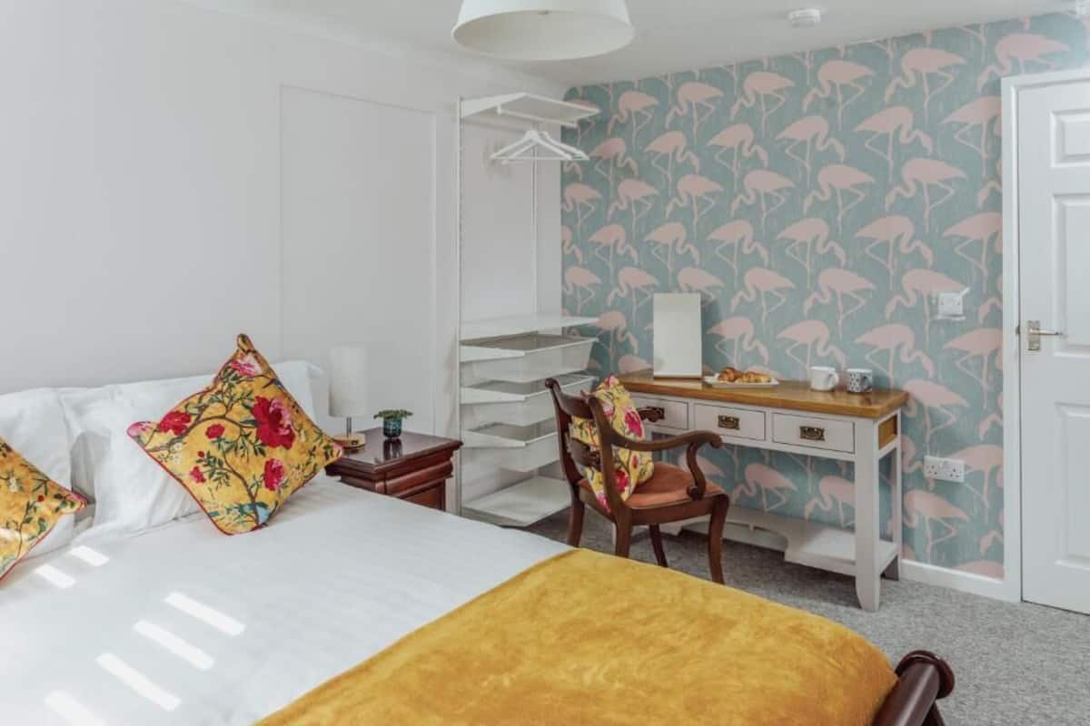 Una habitación de hotel con cama, escritorio, silla, armario y puerta.