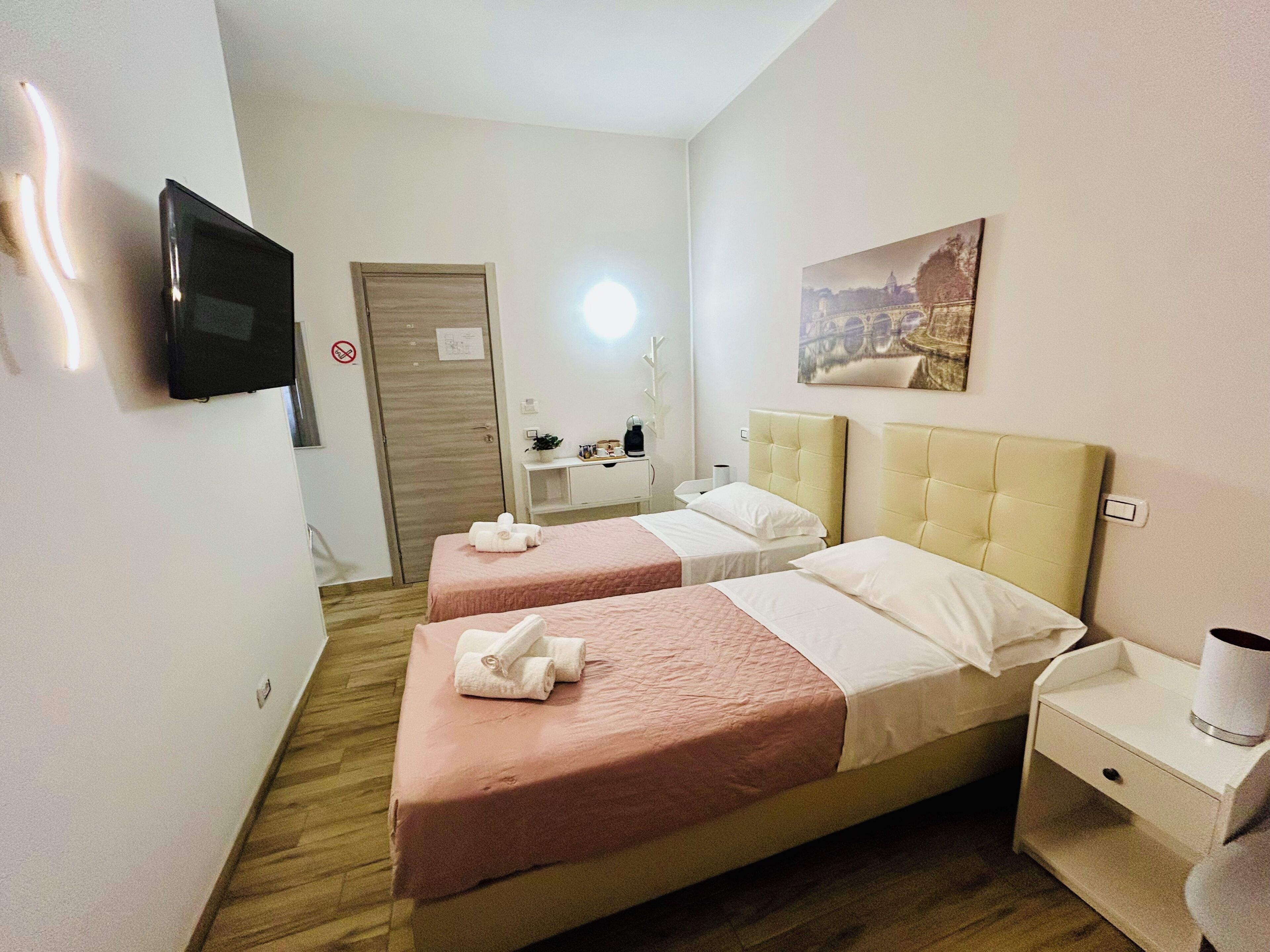 Habitación de hotel con dos camas, televisor, un cuadro, escritorio y mesita de noche.
