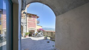Un callejón estrecho con un muro de piedra, una motocicleta estacionada y un edificio con balcón.
