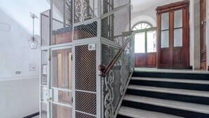 Eine Treppe mit Metallgeländern und Holzhäuschen, die zu einem Raum mit einer großen Holztür und einem Fenster führt.