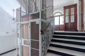 Eine Treppe mit Metallgeländern und Holzhäuschen, die zu einem Raum mit einer großen Holztür und einem Fenster führt.