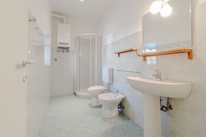 Un bagno moderno con toilette, bidet e cabina doccia.