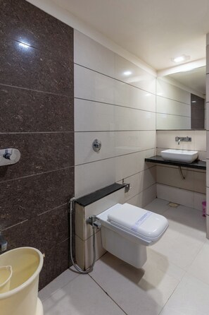 A modern bathroom with a toilet, sink, and shower. - HOTEL ASHISH (Ahmedabad)