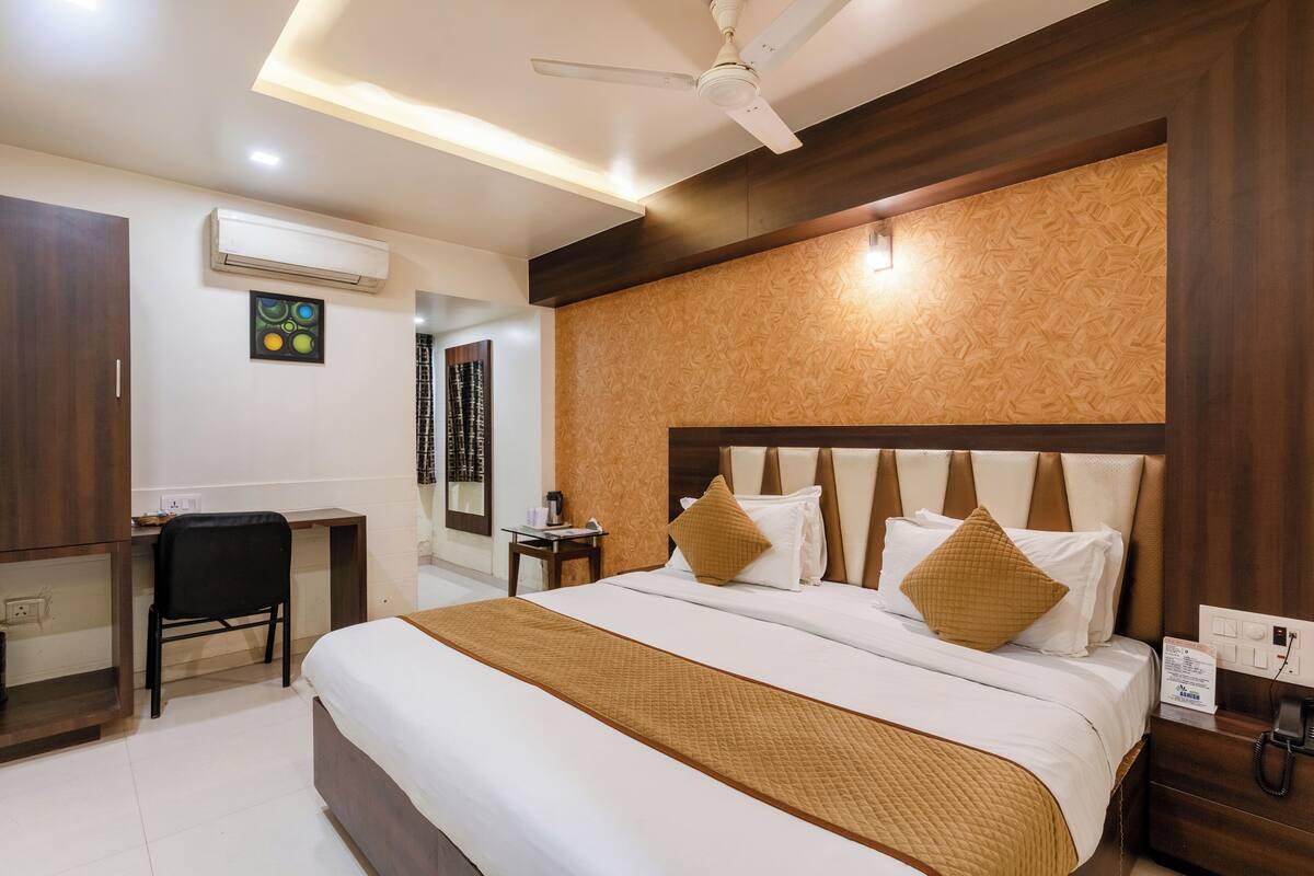 A hotel room with a bed, desk, chair, and a telephone.