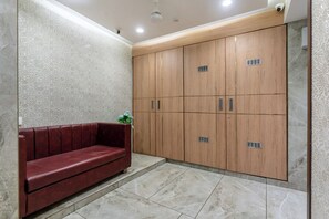 A room with a red sofa, a wooden wardrobe, and a patterned wall. - HOTEL ASHISH (Ahmedabad)