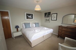Une chambre bien rangée, avec un lit, une table de chevet, une commode et une chaise.