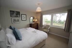 A bedroom with a bed, a dresser, a chair, and a window with a view. - Thurlestone - dog friendly sleeps 6 in premier location with sea views & garden. (Kingsbridge)