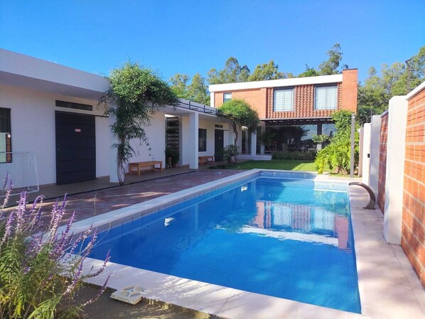 Une maison moderne dotée d’une piscine, d’un patio couvert et d’une façade en briques.