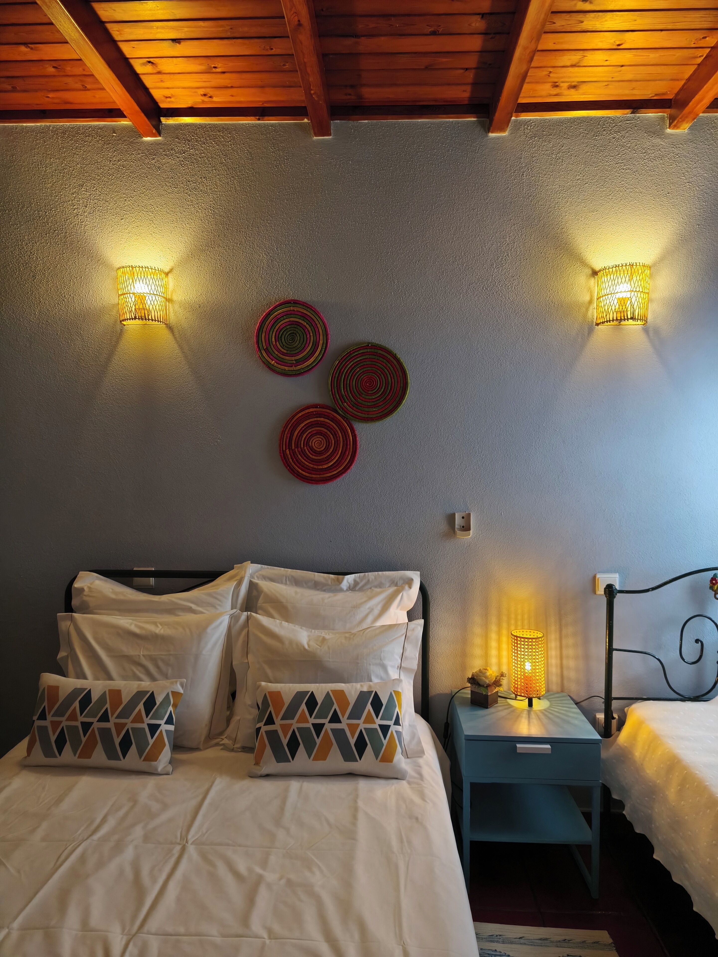 Une chambre à coucher avec un lit, des oreillers, une table de chevet, une lampe et des appliques murales.