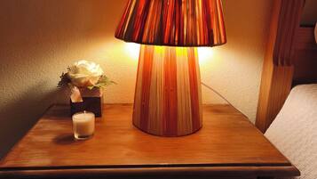 Une table de chevet en bois, avec une lampe, une bougie et une petite plante.