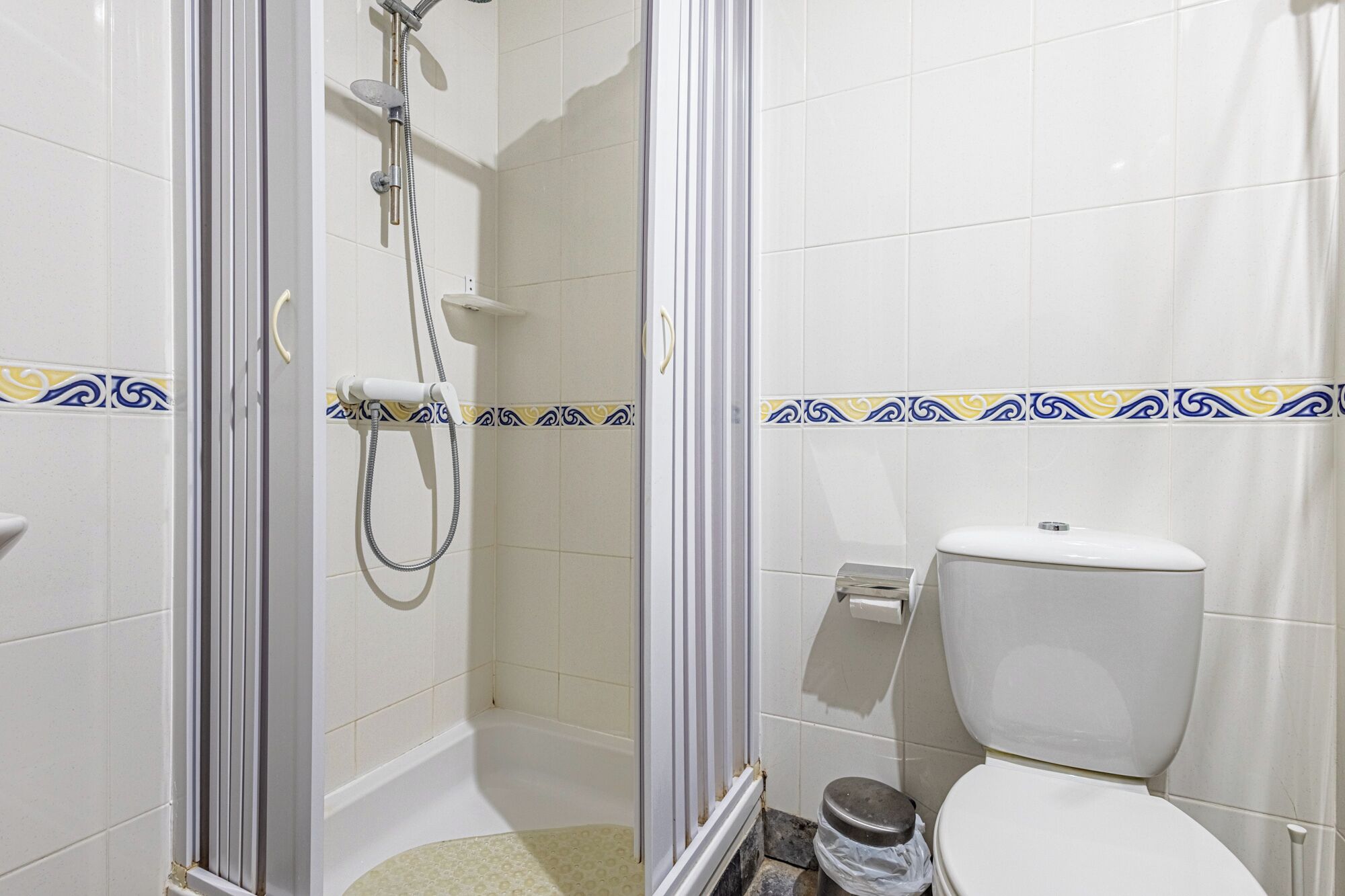 Une salle de bain équipée d’une douche, de toilettes et d’une poubelle.