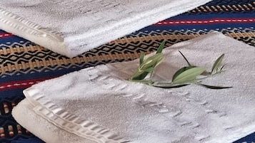 Two neatly folded towels with a leaf decoration on a patterned rug.