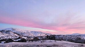 A snow-covered mountain landscape with houses and a pink sky.