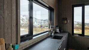 Eine Küche mit großem Fenster, einer Kaffeemaschine und einer Flasche Olivenöl auf der Arbeitsfläche.