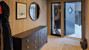 A wooden interior with a dark dresser, a framed picture, a mirror, and a door leading outside.