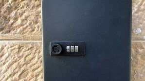 Un objet noir et rectangulaire, doté d’un cadran circulaire et de quatre boutons sur une surface texturée.