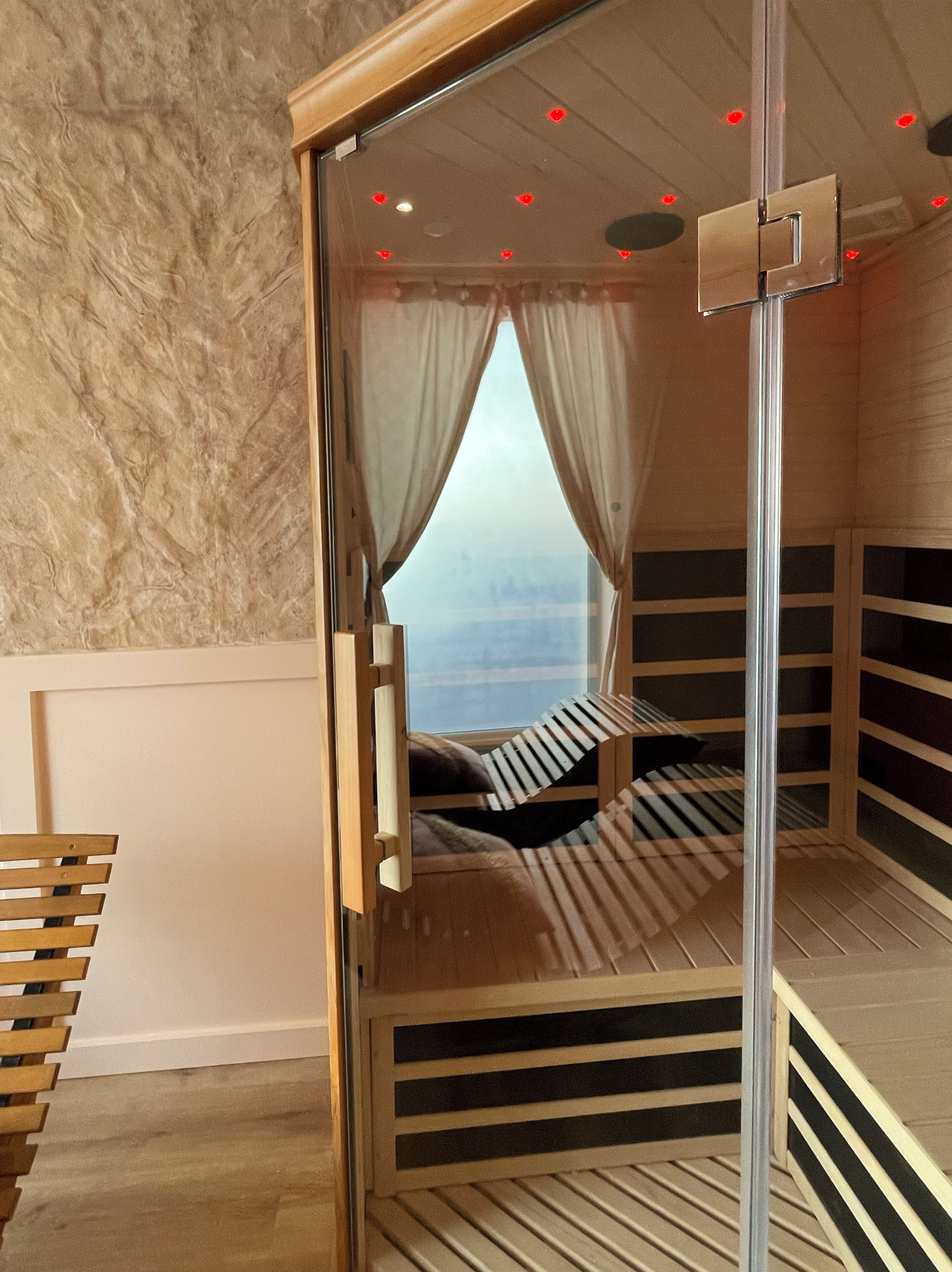 A bunk bed with a glass enclosure, a wooden ladder, and a view of the sky through the window.