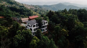 Um edifício moderno de dois andares rodeado por uma floresta densa, com vista desobstruída para a paisagem circundante.