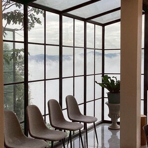 A room with a large glass window, three chairs, and a potted plant. - Mei Nai Home (Pua)