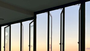 A room with large floor-to-ceiling windows offering a view of a mountainous landscape. - Mei Nai Home (Pua)